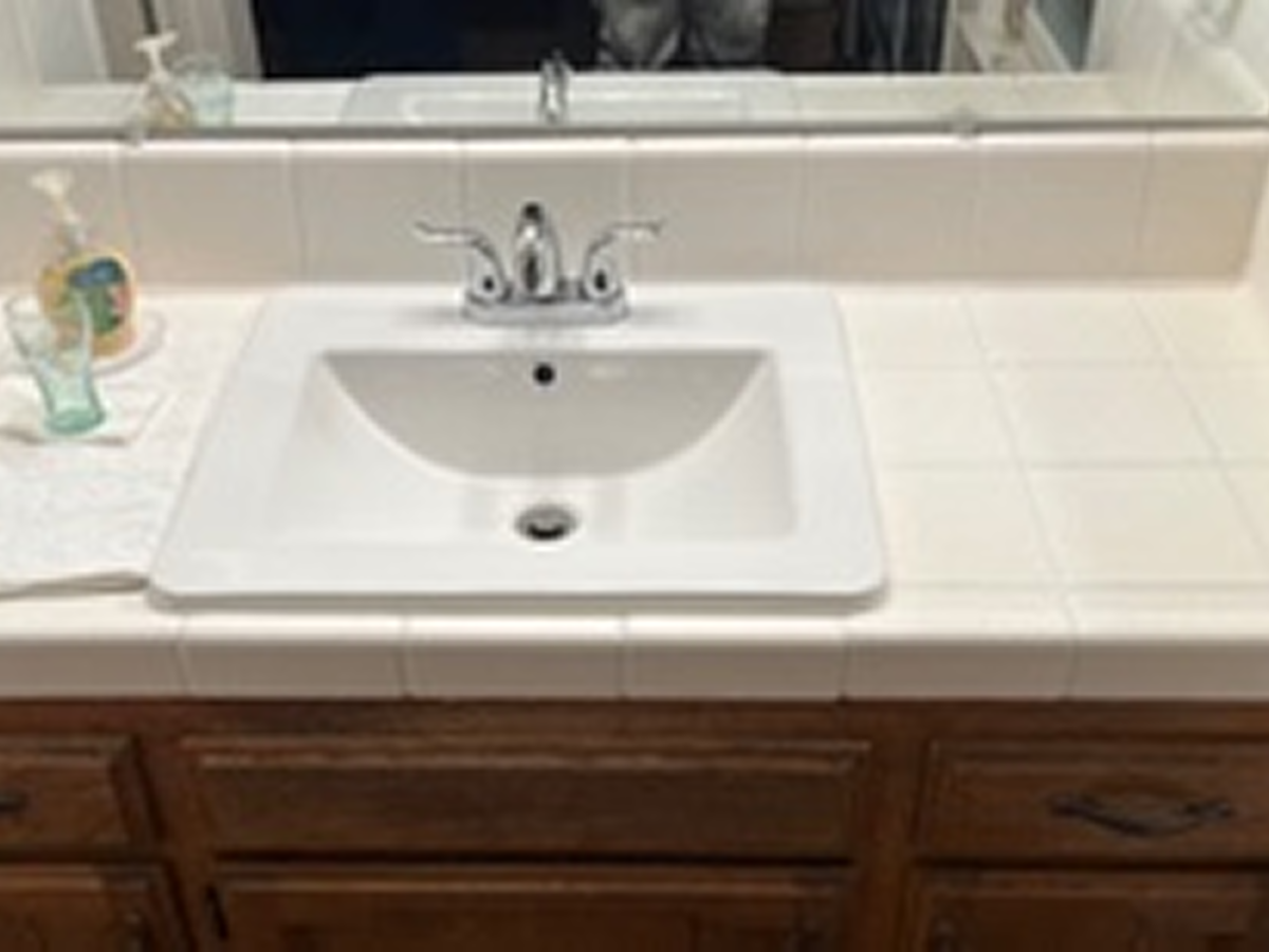 Professional performing sink refinishing in a residential kitchen.