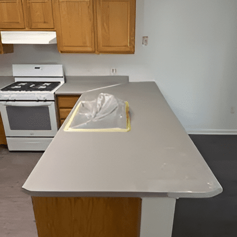 Technician performing countertop refinishing in a residential kitchen.